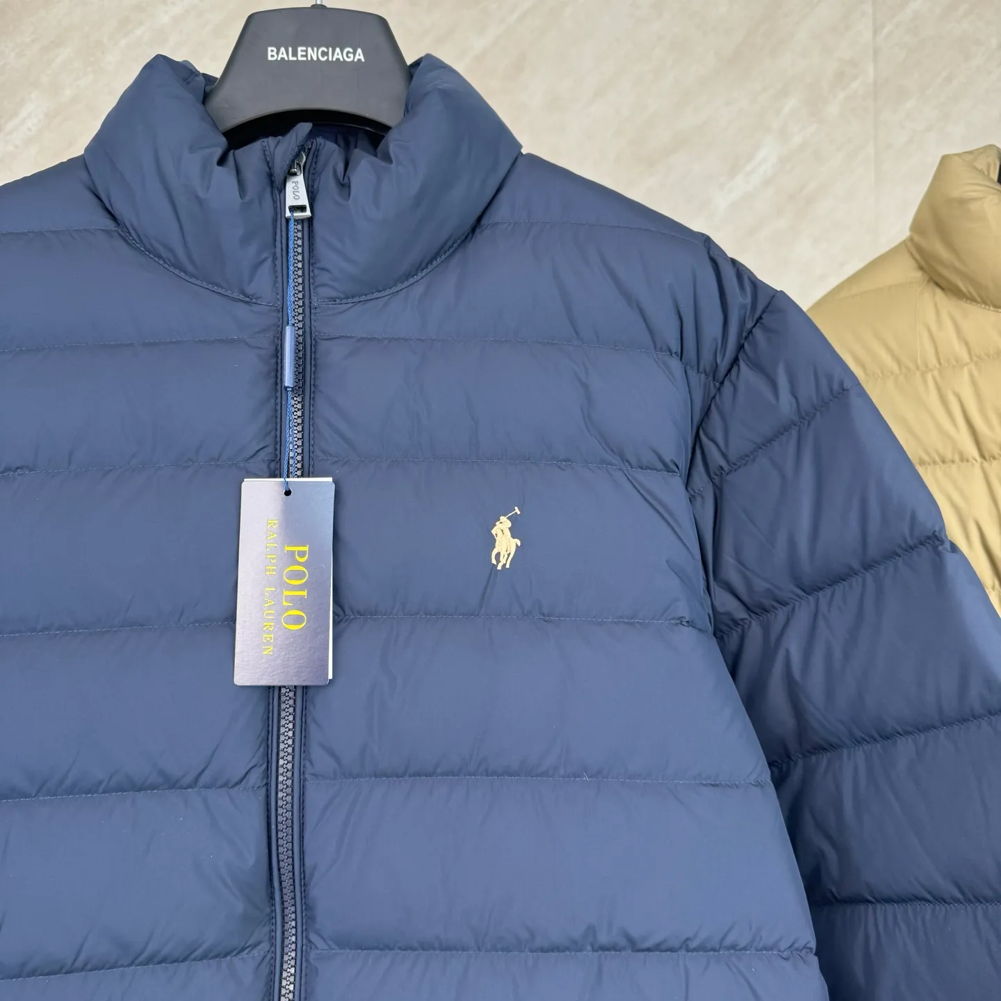 P930 lightweight down jacket size s m l xl Nylon fabric has good windproof and waterproof properties, which can effectively block the intrusion of wind and rain from the outside and keep the inside dry, suitable for wearing in humid or rainy environments.  The red label on the chest is made with an imported MECLO embroidery machine. The original pattern is scanned first, and then high-quality silk thread is used to make a pattern. The density effect is adjusted by continuous pattern making.  Exquisite details: the zipper design is simple and elegant, easy to operate; the closing design of the cuffs and hem effectively prevents the intrusion of cold wind, improving the warmth and comfort of wearing.  High-quality filling: 90 white duck down is selected, with a weight of 260g, ensuring excellent thermal insulation performance. After strict screening and processing, the velvet is not easy to drill, ensuring durability. The hangtags, wash marks, air holes, and four-button buttons are all customized from the original one-to-one mold.